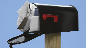 A mail box filled with letters and other junk mail.