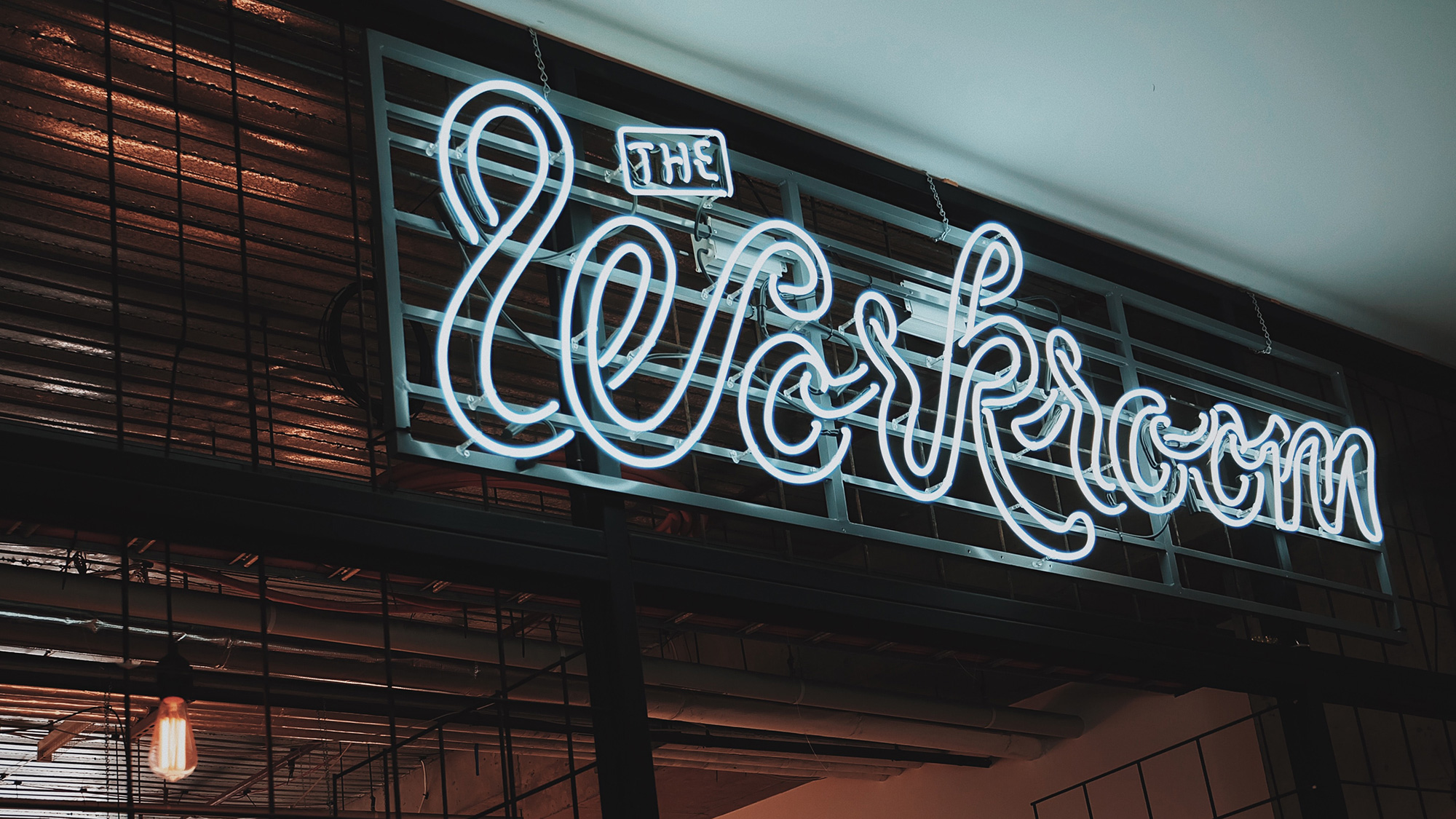 A neon sign that says "The Workroom" above a door