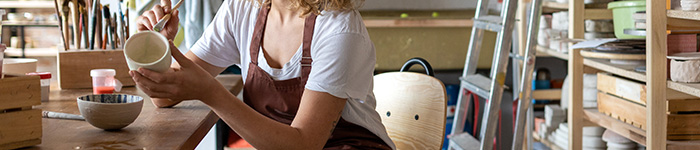 A person detailing a pot in a pottery studio.