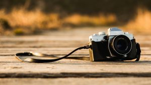 A vintage camera is sitting on a weathered wooden deck