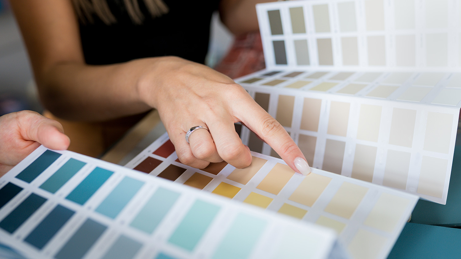 Two people are looking at colour swatches. A woman is pointing at a beige swatch