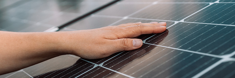 A person running their hand over a solar panel.