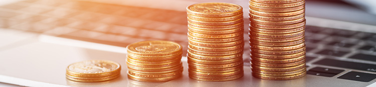 Four stacks of coins, in an increasing amount from left to right, sit on top of a laptop keyboard.