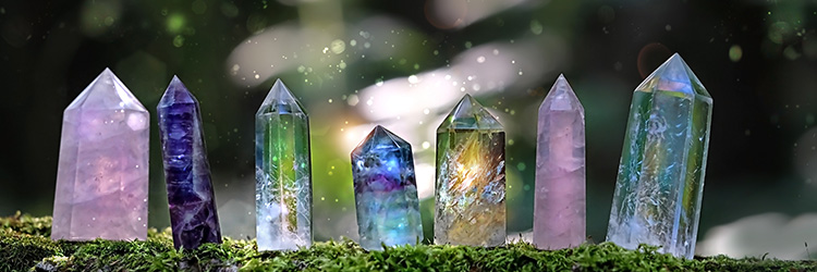 A row of seven crystals standing on a moss-covered shelf.