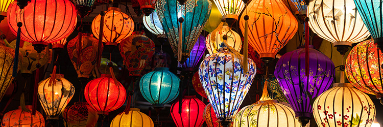 A collection of brightly illuminated silk lamps hanging from a ceiling.