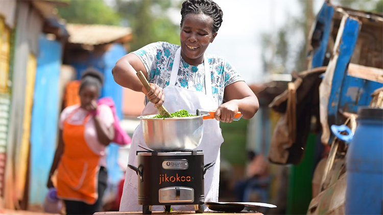 A woman is stirring food that is on top of a cookstove.